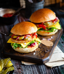 two homemade burgers with fried chicken, lettuce, cheese, onion, pickled cucumbers, ketchup