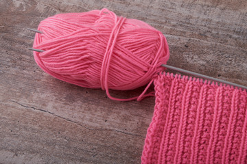 knitting sweaters, or a scarf with a red pattern, thin knitting needles on a white wooden background. Close-up. Copy space.
