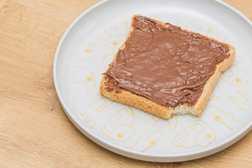 Chocolate sauce melted over a bread slice on a white plate