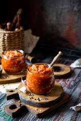 two glass jars with home made red vegetable caviar, ratatouille, ragout on wooden brown boards