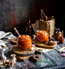 two glass jars with home made red vegetable caviar, ratatouille, ragout on wooden brown boards