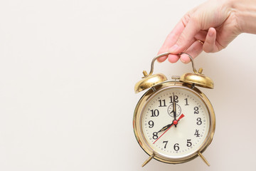 Female hand holds a vintage alarm clock. The concept is to wake up to work. Time to work