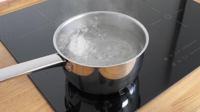 Chicken eggs boiling in stainless steel pan in water.