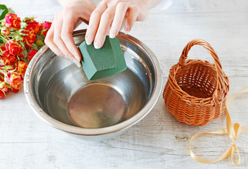 Woman shows how to make a floral arrangement with roses inside the wicker basket. Mother's day gift