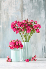 Bouquet of pink roses in blue ceramic vase. Postcard motif.