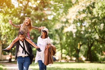 Mother and father with their daughter after school have fun together.