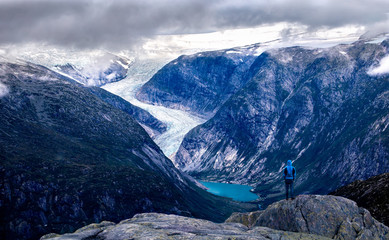Hiker looking at nigardsbreen glacier from the summit of myrhyrna mountain in jostedalen, norway