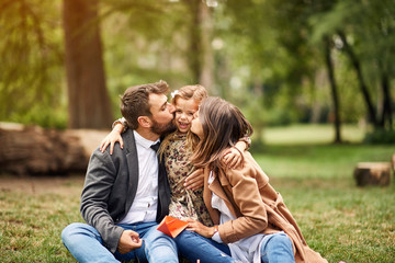 Happy childhood - parents kissing their little child.