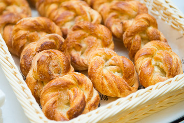 Sweet buns in a basket on a table close-up.