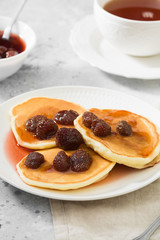 Pancakes with strawberry jam on a white plate. Gray background