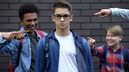 Boy boldly looking into camera despite mockery of classmates, resisting bullying