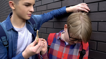 Teenage student extorting pocket money from classmate, school bullying, closeup