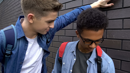 Arrogant boy mocking african american student, verbal abuse, discrimination
