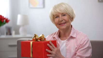 Smiling senior female holding gift box, happiness, womens day celebration