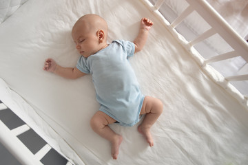 Top view wide angle sleeping newborn baby lies in a crib arms and legs outstretched - obrazy, fototapety, plakaty