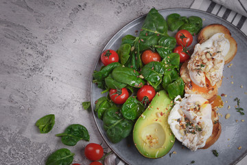 Toasts with avocado and poached egg, tomatoes and spinach, On a light gray background, Fresh morning breakfast