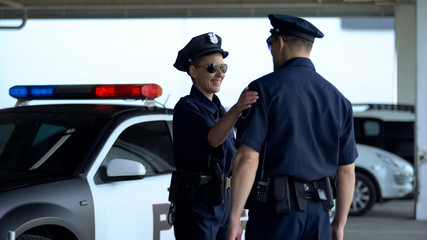 Obraz premium Positive male and female police officers communicating on parking lot, on duty