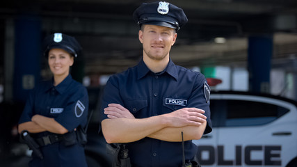 Kind police officers smiling standing near police station, ready to help, order - 286986663
