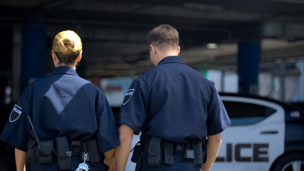 Fototapeta na wymiar Two police officers walking to car, patrolling district together, back view