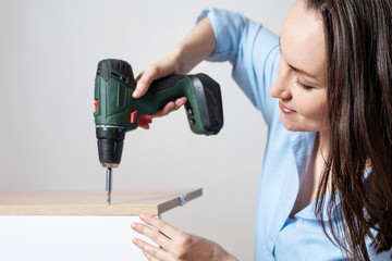 Closeup portrait of a European woman with a screwdriver in hand, collects furniture