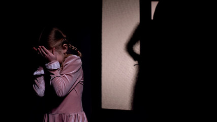 Little girl afraid of dark male silhouette opening room door, horror nightmare