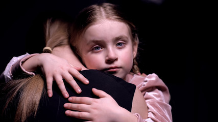 Little girl looking into camera and hugging mother, long separation, close-up