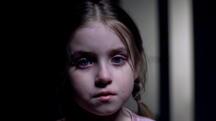 Little crying girl looking at camera, victim of domestic violence, childs rights