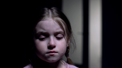 Girl crying in dark room, bullying victim, kids rights protection, childhood