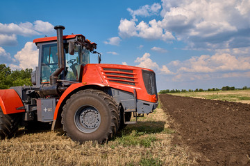 Obraz premium Tractor plows field, cultivators soil for sowing