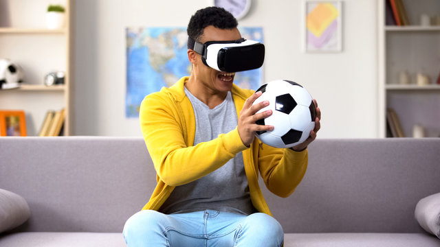 Mixed-race teen boy in VR headset holding ball, pretending to be goalkeeper