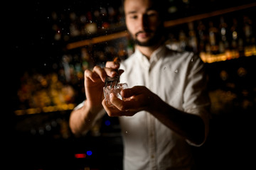 Bartender crushing ice cube with a special instrument
