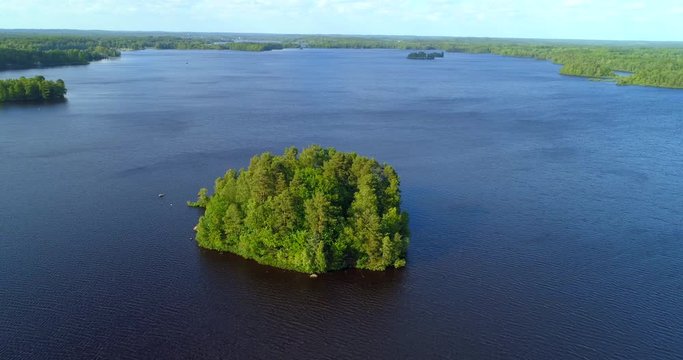 Aerial: Trees on island in lake against sky - Smaland, Sweden