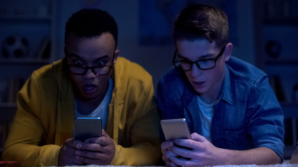 Multiracial male friends surfing net late at night, gadget addiction, eyesight