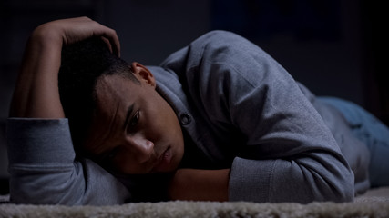 Fototapeta na wymiar Depressed african-american teenager suffering loneliness in dark room, abuse