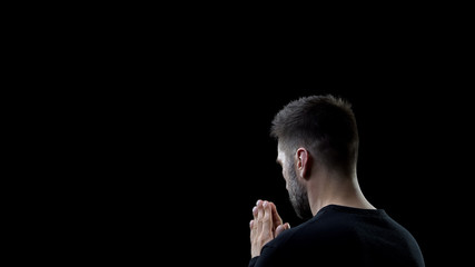 Praying man on black background, sins forgiveness, spiritual inspiration, help
