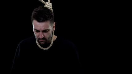 Disappointed man in rope noose on black background, life crisis, depression