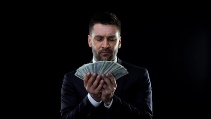 Glad male in formal suit holding money, enjoying wealth, financial prosperity