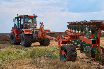 Obraz premium Tractor plows field, cultivators soil for sowing