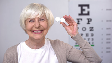 Smiling elderly woman showing lens into camera, patient choice, recommendation