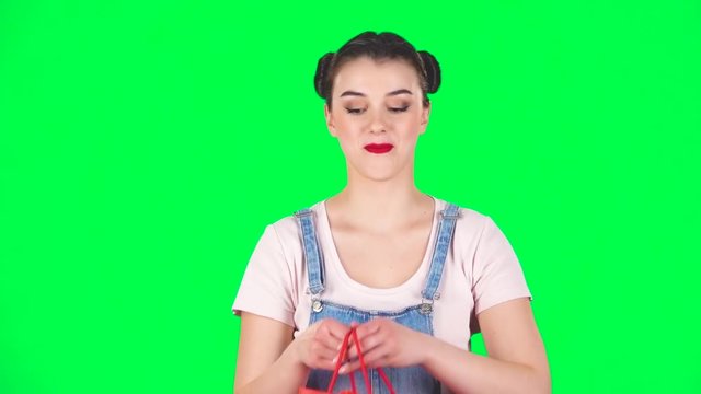 Girl takes out package then looks into it and is very upset on a green screen, slow motion