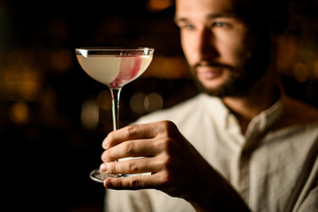Professional bartender presenting a cocktail in the glass decorated with pink ice cube