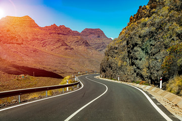Road among the high mountains with sunset view and mountain background.