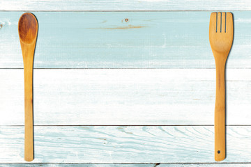 Wooden spoon and fork on turquoise wooden table. Kitchen and cooking concept.