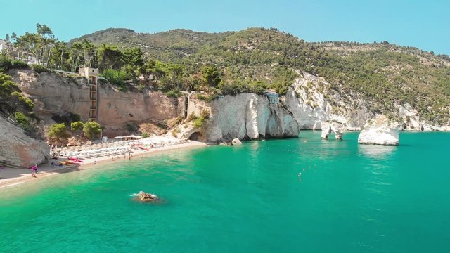 Summer touristic destination in Puglia, Italy: Faraglioni di Puglia Baia delle Zagare - Beach and faraglioni rocks formation (stacks, coastal rocks eroded by waves)