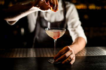 Bartender serving a cocktail in the glass adding a lemon juice
