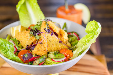 A plate of Crispy Calamari Salad with lettuce, radish, lemon, tomatoes, asparagus  and avocado.
