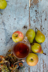 autumn harvest composition with apples pears cup of tea and dry healing herbs on wooden blue table background