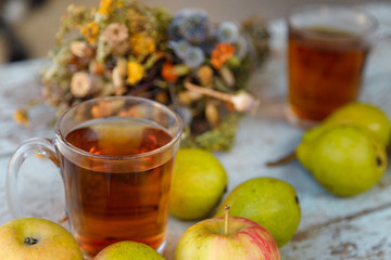 autumn harvest composition with apples pears cup of tea and dry healing herbs on wooden blue table background