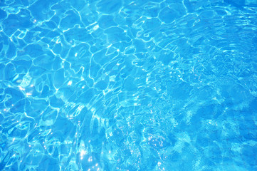 Swimming pool bottom caustics ripple and flow with waves background. Summer background. Texture of water surface.