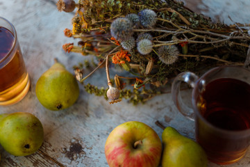 autumn harvest composition with apples pears cup of tea and dry healing herbs